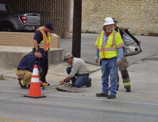 ERICK MITCHELL | DISPATCH RECORD Lampasas Fire Department firefighters and Atmos Energy representatives look to investigate a possible natural gas leak underneath a manhole on Fourth Street between Live Oak and Western Avenue.