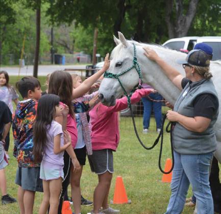 Students reach out to touch a horse on display during Ag Safety Day at Hanna Springs Elementary School. ERICK MITCHELL | DISPATCH RECORD