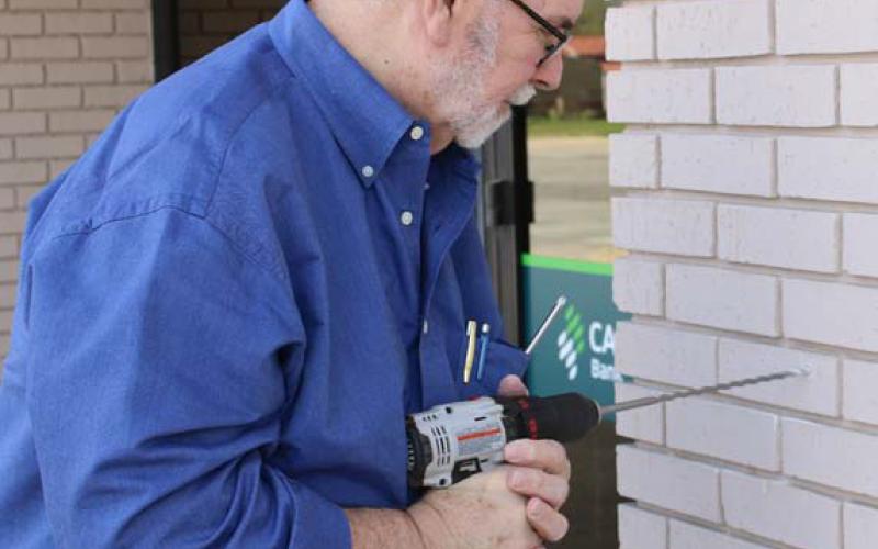 Historical commission member Tom Welch helps mount the plaque at the bank. mason hines | dispatch reacord