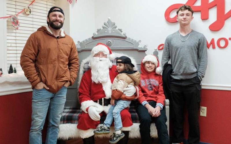 Adam Barrios, Adam Jr., Jackson and Jayden Barrios pose for a photo with Santa Claus in the Ajinomoto lobby on Saturday. Santa made an appearance to hear Christmas wishes before joining the Holidazzle Parade later that evening. gabriela sangache |Dispatch Record
