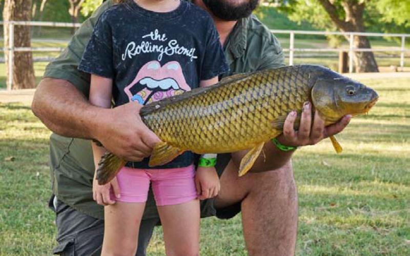 Teagan Eicher, 5, poses with the 27-inch fish she caught during KidFish on Friday evening. She is pictured here with her father, Derrick Eicher. ADAM BARRIOS | DISPATCH RECORD