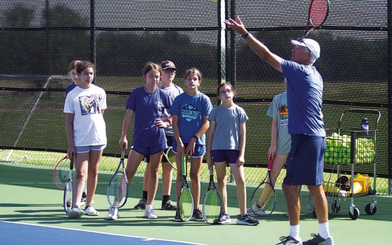 Kenneth Peiser shows young campers some serving tips at camp on Friday. HUNTER KING | DISPATCH RECORD