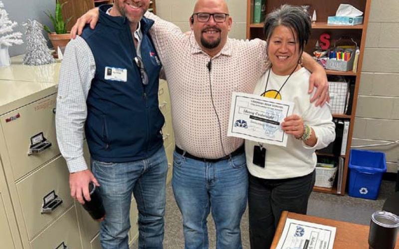Sherry Cartwright, who serves as high school registrar, was honored in December for her work in the front office. With her are Clay Phillips, at left, of Texas Farm Bureau Insurance, and Assistant Principal Ryan Race. Cartwright “always has a smile on her face and spreads kindness to everyone she sees,” Race said. COURTESY PHOTO