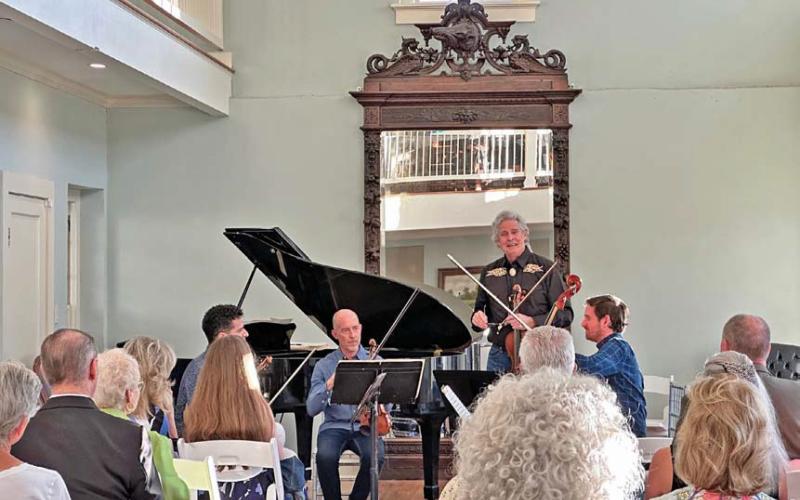 Bruce Williams introduces fellow musicians Patrice Calixte, Douglas Harvey and Dr. Stephen Redfield as they prepare to perform “Quartets at the Keystone” for the audience at the Keystone Star Hotel ballroom during last year’s Lampasas Chamber Music Festival in June. file photo