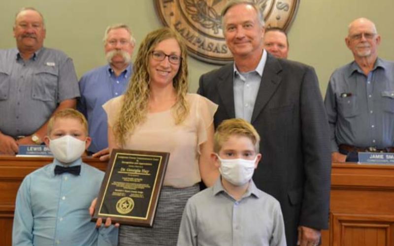 Dr. Georgia Hay stands with her sons Chase, left, and Jacob, along with County Judge Randy Hoyer on Monday, when the physician was honored for her service to the community. Back row from left are county commissioners Mark Rainwater, Lewis Bridges, Jamie Smart and Bobby Carroll. MONIQUE BRAND | DISPATCH RECORD