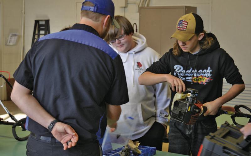 Edward Gold (with back to camera), who teaches the small-engine class at Lampasas Middle School, has been pleased with the progress shown by students this year. Hunter Jennings, at right, works on diagnostics during Friday’s class period as a colleague looks on. ERICK MITCHELL | DISPATCH RECORD