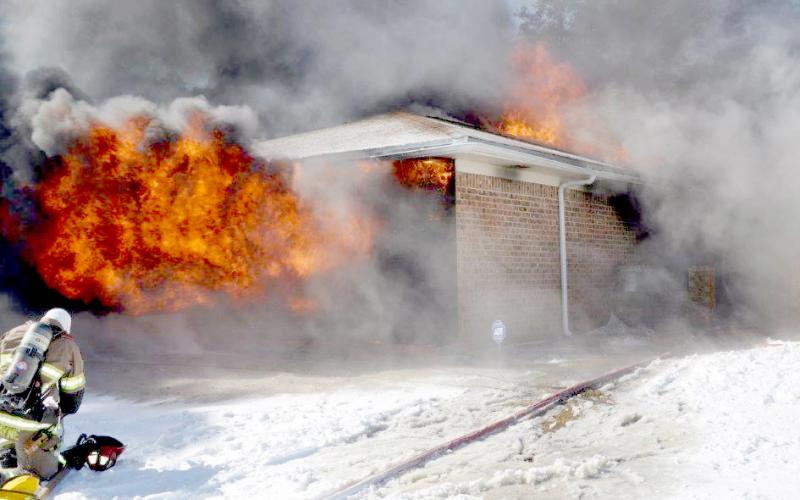 Lampasas Fire Department firefighter Jared Payne works the scene of a structure fire on Monday. Fire departments have seen a call volume far above average this week.