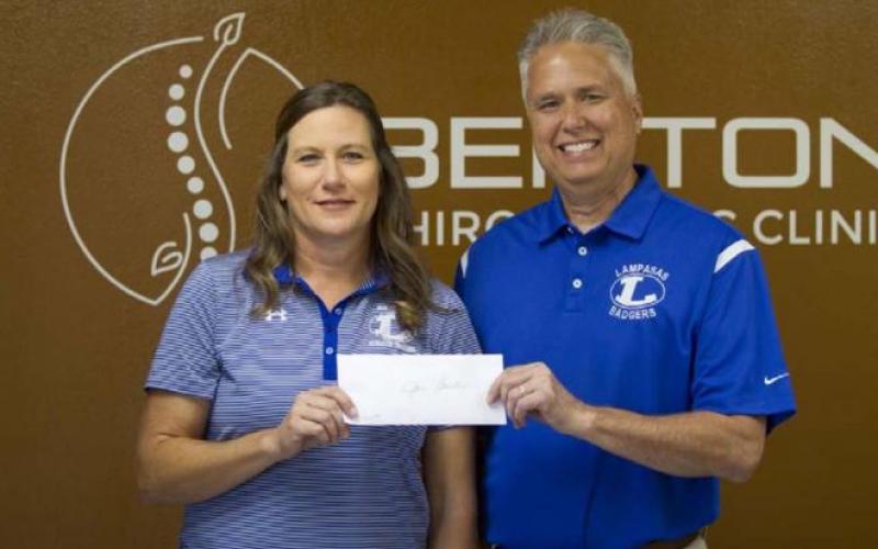 Jan Brister receives a check from Craig Benton for $500 that will go toward improvements for the athletic training department. HUNTER KING | DISPATCH RECORD
