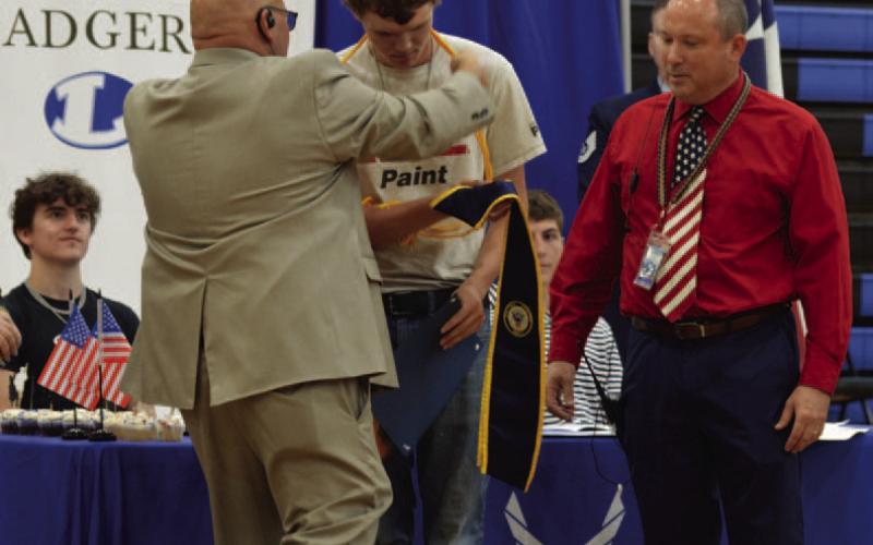 Ethan Walker receives a graduation cord from Assistant Principal Ryan Race to signify the senior’s commitment to the Navy, as Principal Paul Weinheimer looks on. Walker was one of 11 students recognized during Monday’s Armed Forces signing ceremony at Lampasas High School.