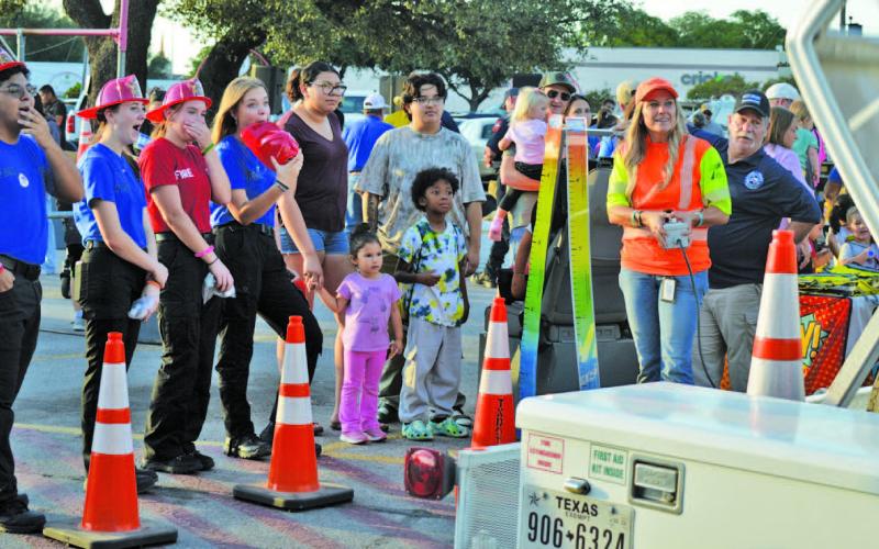 At left, Lampasas High School fire and EMT students look in awe at the Texas Department of Transportation’s demonstration showing how an unrestrained child moves freely in the vehicle during a rollover accident. The simulation helped emphasize the imporantce of having a properly-fitted child safety seat. For more photos from Tuesday’s National Night Out event in Lampasas