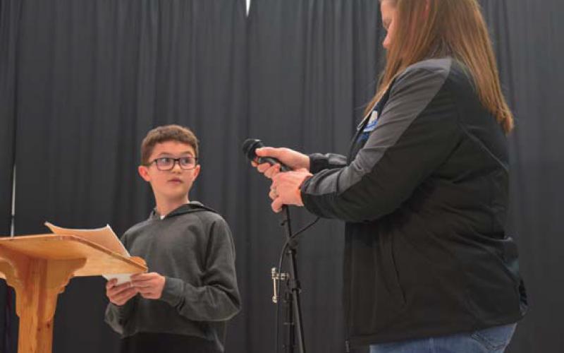 Jace Walkowiak receives the microphone from Taylor Creek counselor Carisa Brown before reading his poem aloud. erick mitchell | dispatch record