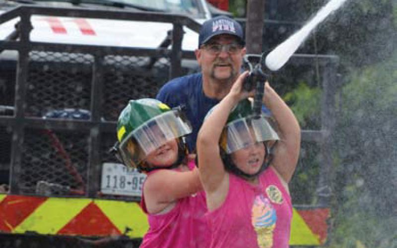 Lampasas Volunteer Fire Department’s Joe Kocian assists Realynn Escobedo and Emmersyn Johns in a game of water tug-owar on Friday. hunter king | LAMPASAS DISPATCH RECORD