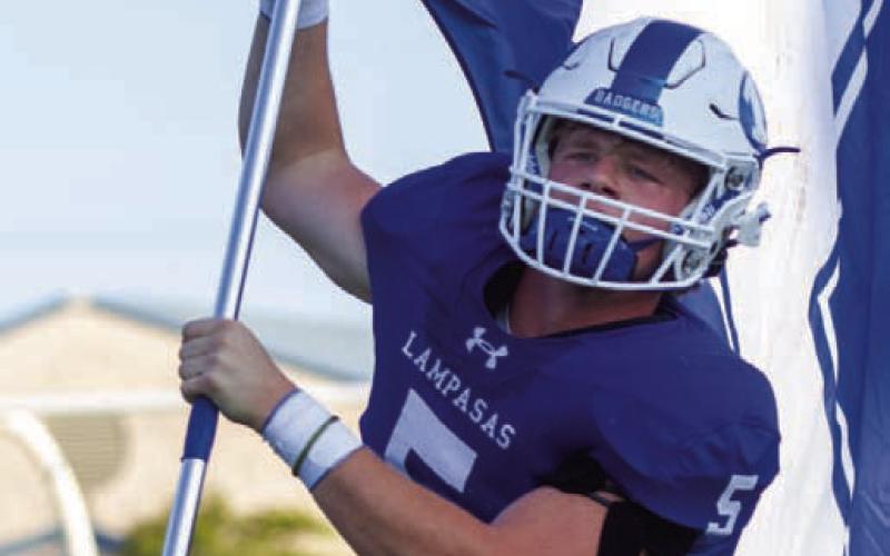 Cayhil Isom, a senior tight end for the Badgers, runs out of the tunnel with the Lampasas flag. On Senior Night last week, Isom made a crucial catch for the Badgers in the back of the end zone during overtime. ANA SOFIA MEYER | DISPATCH RECORD
