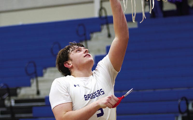 Aidan Nuckles reaches up to cut down the net as the Badgers celebrate their district title. HUNTER KING | DISPATCH RECORD
