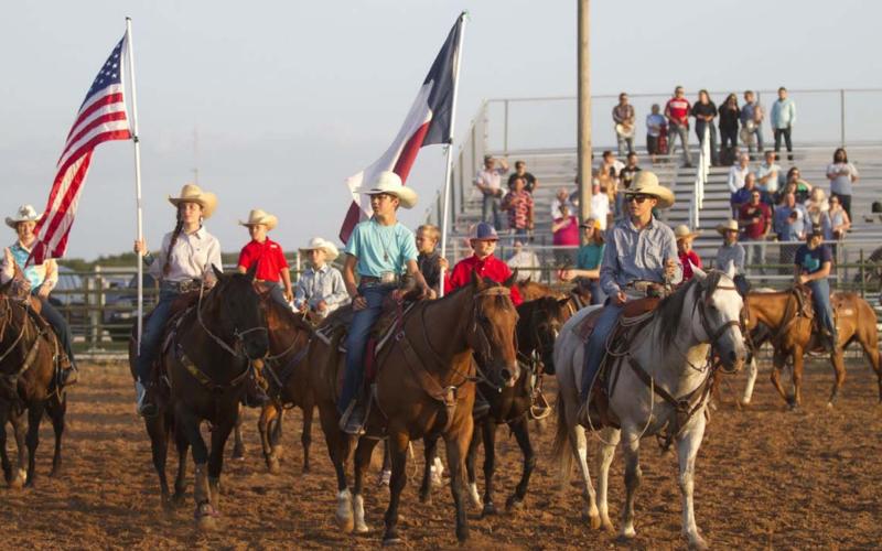 Riders at the Lometa FFA Junior Rodeo ride through the Bar 3 Arena in Lometa with the American and Texas flags as the rodeo kicked off Friday night. HUNTER KING | DISPATCH RECORD