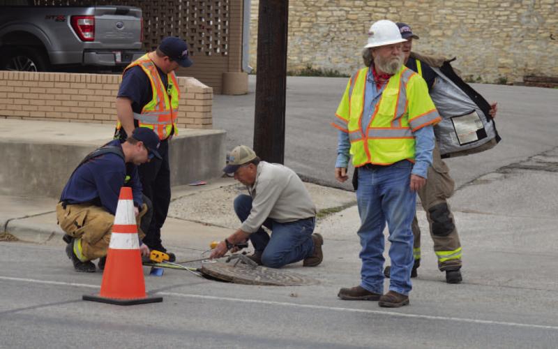 ERICK MITCHELL | DISPATCH RECORD Lampasas Fire Department firefighters and Atmos Energy representatives look to investigate a possible natural gas leak underneath a manhole on Fourth Street between Live Oak and Western Avenue.