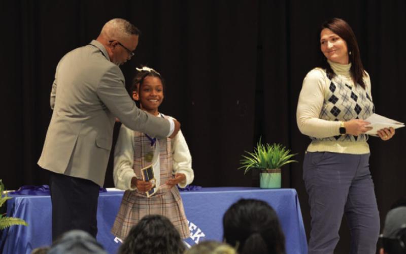At left, Principal Mark Sheppard places a medal on third-grade student Mila Culley for her master’s degree achievement during Thursday’s ceremony. ERICK MITCHELL | DISPATCH RECORD