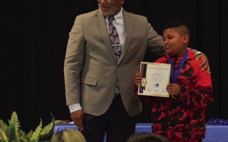 Fourth-grade student Eli Vazquez holds his master’s degree certificate alongside Taylor Creek Elementary Principal Mark Sheppard. ERICK MITCHELL | DISPATCH RECORD