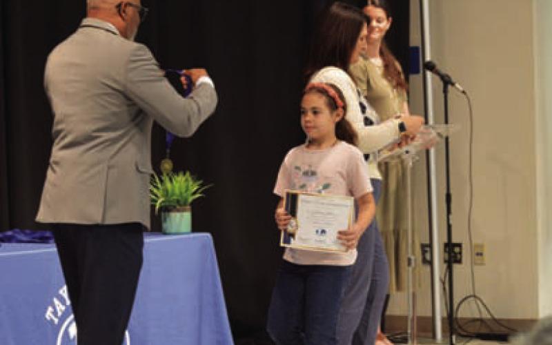 Fourth-grade student Cataleia Chaves makes her way toward Principal Mark Sheppard to receive her master’s degree program medal honoring her achievement. ERICK MITCHELL | DISPATCH RECORD