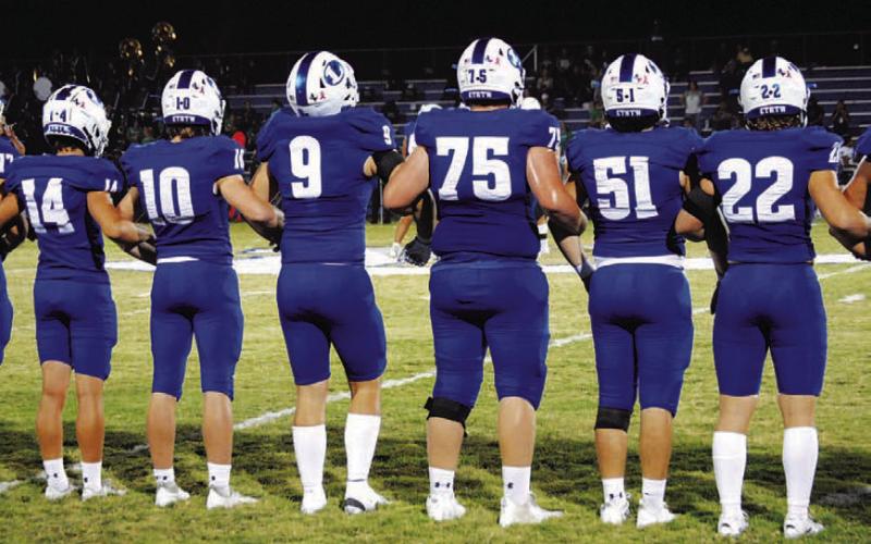 The Badgers stand locked arm in arm during the coin toss before every game. HUNTER KING | DISPATCH RECORD