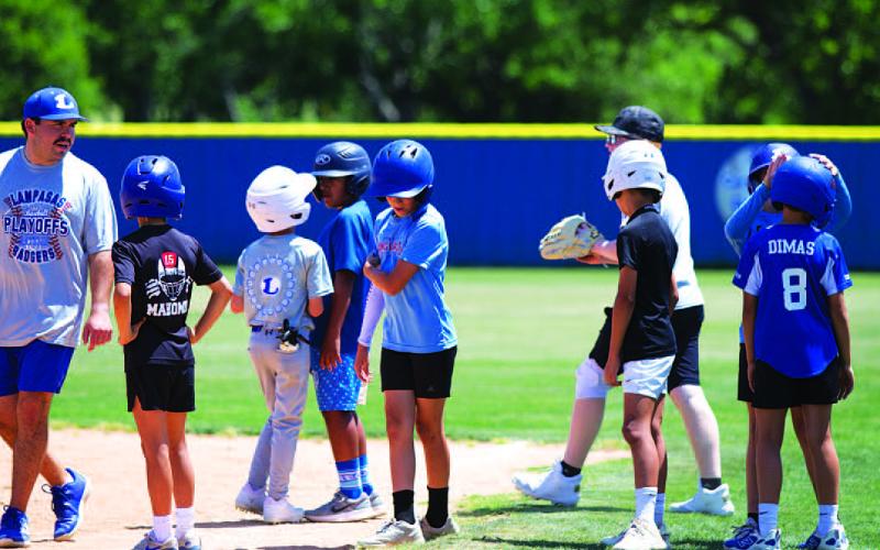 Assistant coach Jaden Napolez, left, talks to some campers about base running this week. HUNTER KING | DISPATCH RECORD