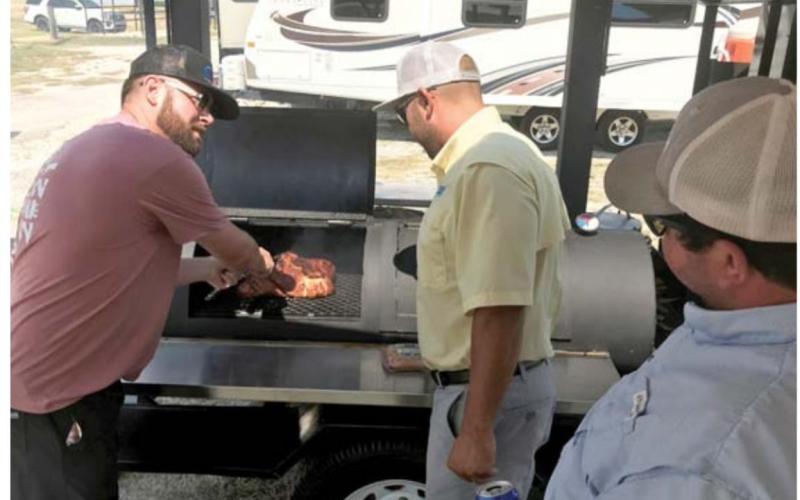 Teammates TJ Wright, at left, Brodi Bocnegra and Wes Canales prepare their meat in last year’s LTX BBQ Fest competition. FILE PHOTO