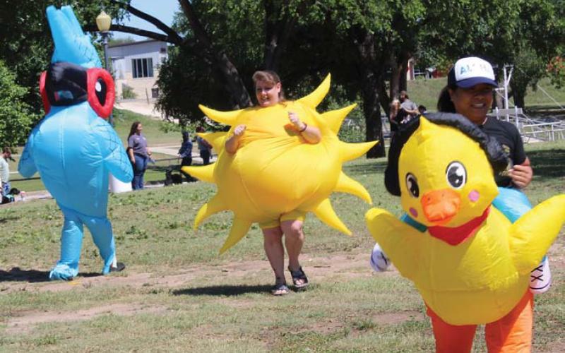From left to right: Krista Spurgeon, Paula Dowdy and Shirley Tolliver rush to the finish line during one of “Woofstock’s” inflatable races. erick Mitchell | dispatch record