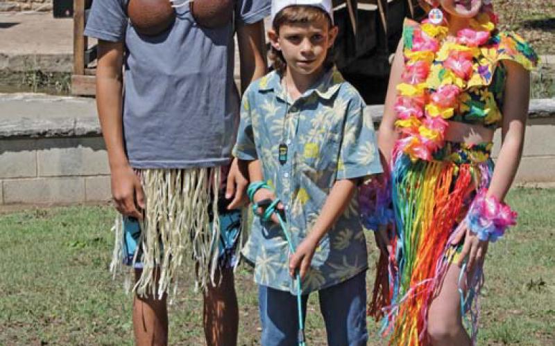 Nate Maceyra, Kohen Black and Rilee Black -- shown left to right -- enter their dog Tobey in the costume contest, dressed in a hula theme. The contest was among the activities offered last Saturday at the “Woofstock” event. chloe cowdrey | dispatch record