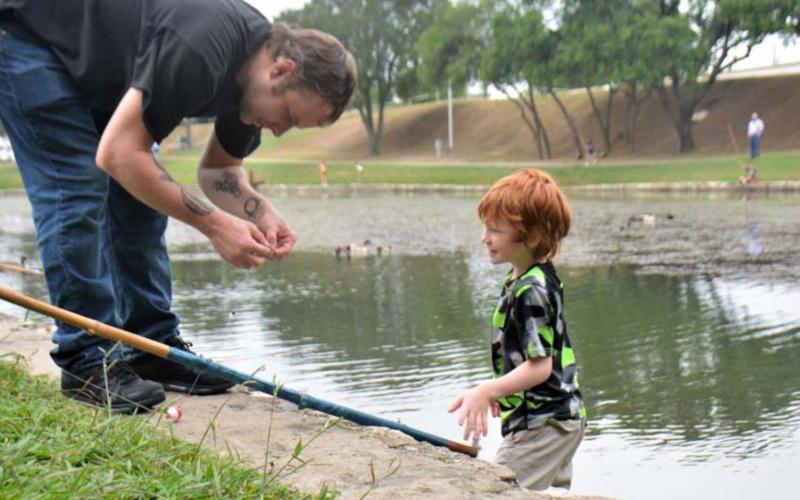 Daniel Chapman prepares a cane pole for his son, 7-year-old Rory Chapman, during the fishing derby Wednesday at W.M. Brook Park. See related photo on page 4. MONIQUE BRAND | DISPATCH RECORD