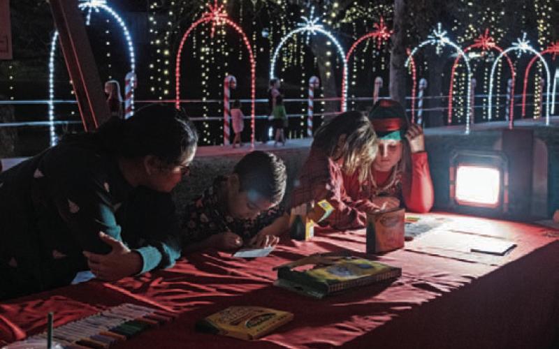 GABRIELA SANGACHE | DISPATCH RECORD Top left, children write their Christmas wish letters to Santa Claus at the Christmas on the Creek event Saturday. Santa and Mrs. Claus made an appearance at W.M. Brook Park that evening to visit with local residents.