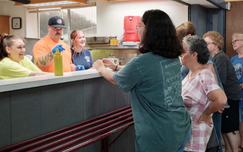Kempner Volunteer Fire Department volunteers Casey Chapman and Alex Hansen, left and second from left, serve hungry fundraiser attendees at the annual BBQ and Auction event on Saturday. The fundraiser regularly garners thousands of dollars for fire department equipment, operation and training. gabriela sangache | dispatch record