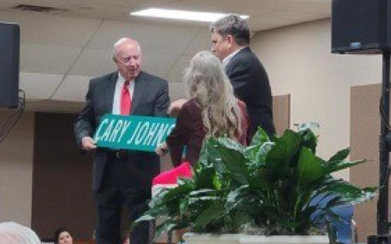 City Manager David Vaughn, at right, and Burnet Mayor Crista Goble Bromley present Cary Johnson with his own street sign. COURTESY PHOTO