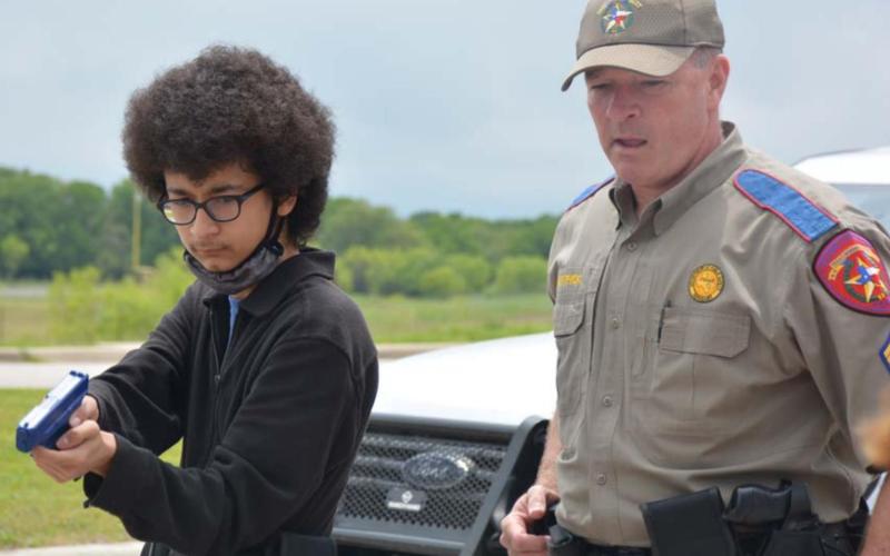 Texas Department of Public Safety Sgt. Ryan McKittrick instructs Lampasas High School freshman Joshua Jass in how to clear a vehicle. MONIQUE BRAND | DISPATCH RECORD