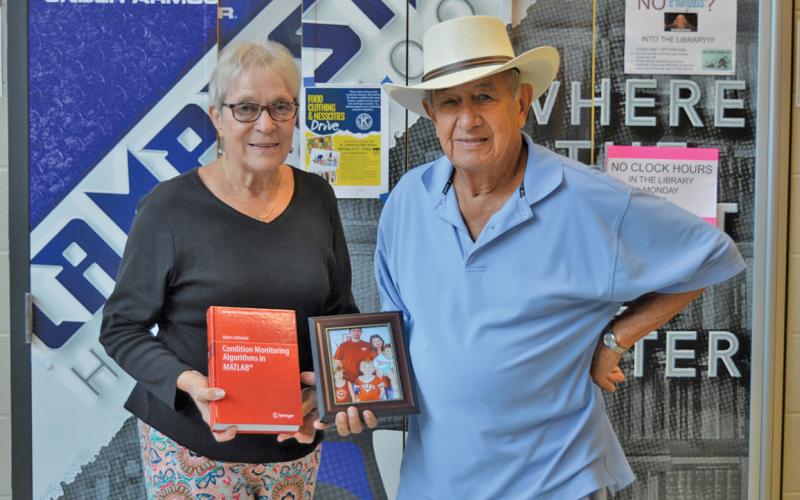 erick mitchell | dispatch record Sherry and Bob Ellis hold a photo of Adam Jablonski’s family and the former LHS exchange student’s published textbook. Jablonski is a university professor now in Poland.