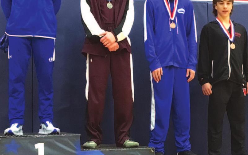Rylan Myers, left, stands on top of the podium after finishing first during the district wrestling meet last week. COURTESY PHOTO