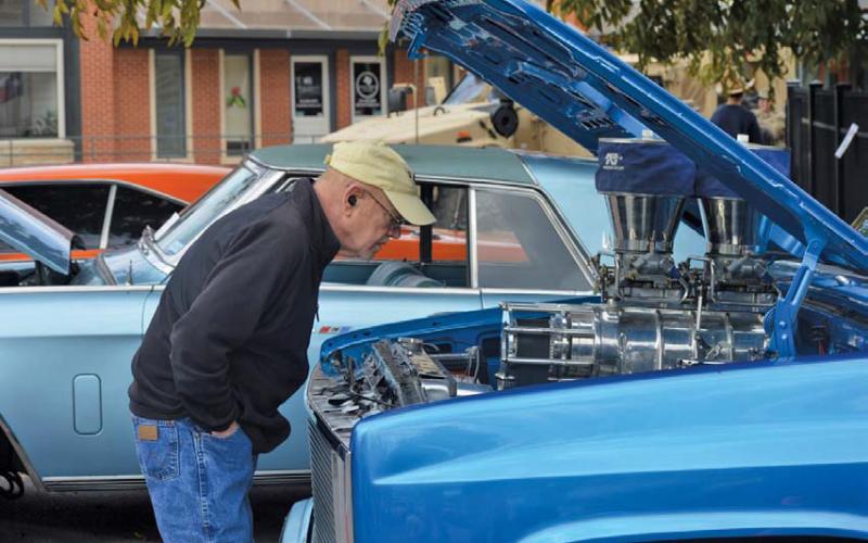 ERICK MITCHELL | DISPATCH RECORD Carl French looks underneath the hood of an antique truck on display Saturday at the Classics at the Classic car show on the downtown square.