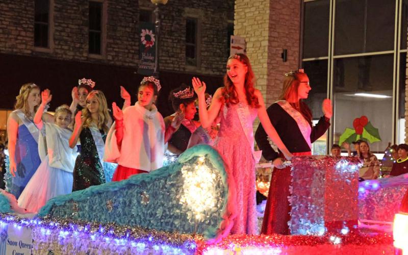 The 2023 Snow Queen Court waves to the crowd during the Carol of Lights Holidazzle Parade on Saturday. The Snow Queen Court was selected earlier that day during a pageant at the courthouse bandstand. JOYCESARAH MCCABE | DISPATCH RECORD
