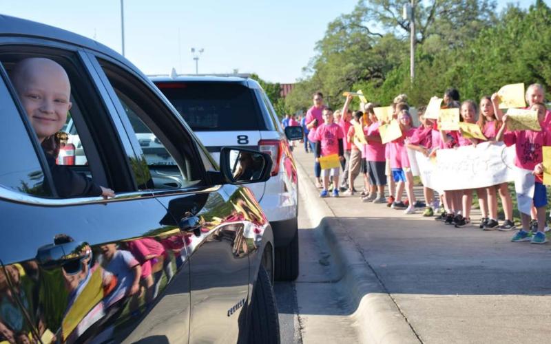 Hanna Springs Elementary School first-grader CJ Cluck, left, is cheered on by his classmates during a drive-by event at the school. He hasn’t seen his teachers or classmates since February, as the student is battling Ewing sarcoma, a rare form of cancer. MONIQUE BRAND | DISPATCH RECORD