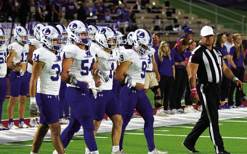 The football team’s captains walk onto the field for the opening coin toss.