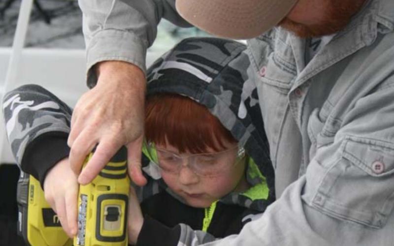 Bear Scout Jesse Parker predrills a hole for lag screws to hold the Cub-Mobile car together, with the help of his father, Seth Parker. SHERRYL-LYNN GOOCH | COURTESY PHOTO