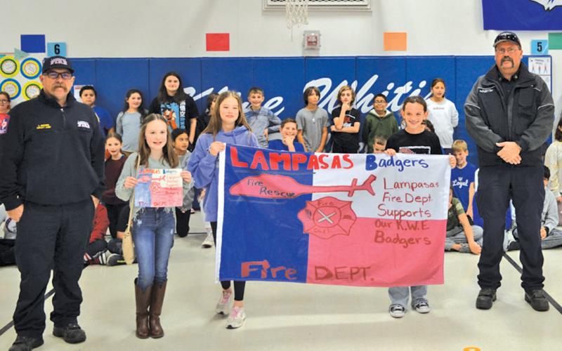 Karlee Tower, second from left, designed the winning Kline Whitis flag for Fire Prevention Week. The Lampasas Fire Department, represented by Deputy Chief Corey Greiner and Fire Marshal JP Harris presented a copy of the flag to Tower and her classmates. erick mitchell | dispatch record