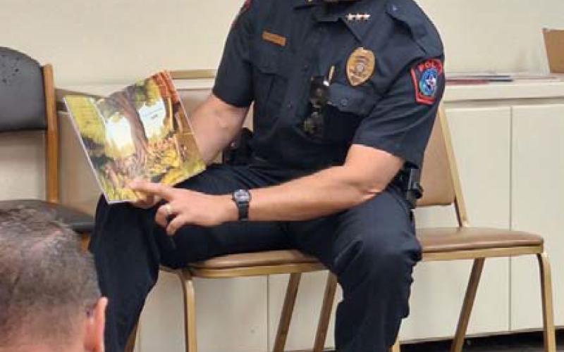 Lampasas Chief of Police Jody Cummings participates in reading a storybook to those gathered for the commuity’s first “See You at the Library” family event. COURTESY PHOTO | DIANNE MOUW