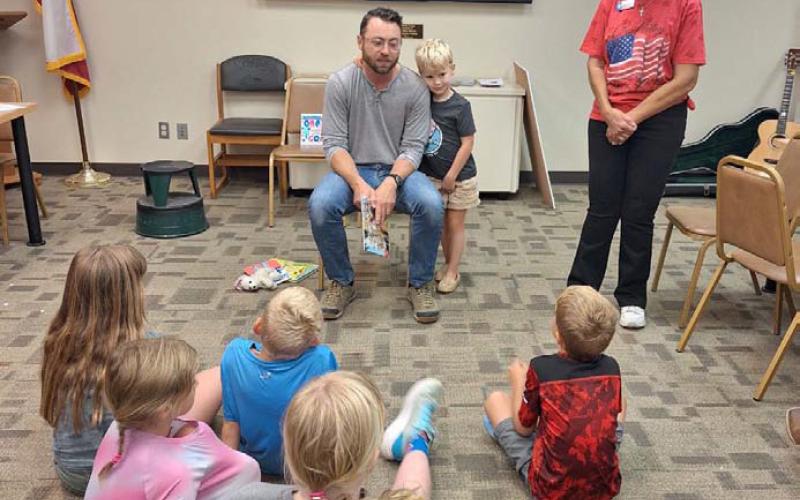 Zach Huckabee, pastor at Lampasas Community Church, visits with a group of children during “See You at the Library,” which organizers called a success. In addition to reading, he also provided music. COURTESY PHOTO | DIANNE MOUW