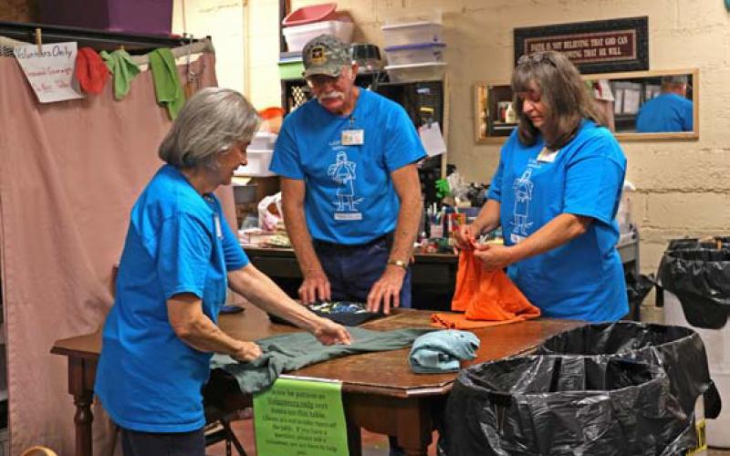 joycesarah mccabe | dispatch record Billy James and Marilyn James stand on one side of the clothing sorting table folding T-shirts, while Frieda Gayheart stands on the other side and assists.