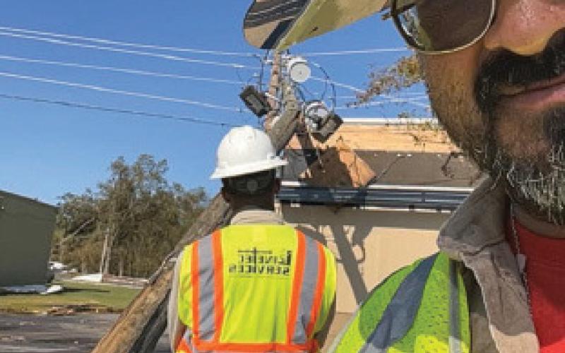Armando Rosales poses for a work selfie that includes in the background a broken power pole caused by heavy winds from Hurricane Helene in Georgia. Rosales spent more than a month on the job assisting in restoration efforts after Hurricanes Helene and Milton struck the Southeast earlier this year. courtesy photo