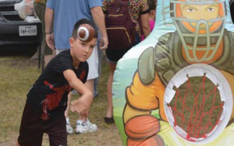 ERICK MITCHELL | DISPATCH RECORD Aiden Norman tries his luck in the football toss at Kids’ Day Activities during Spring Ho week.