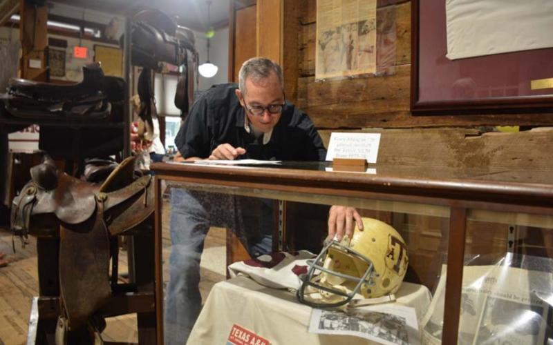 Museum board member John Fingerhut props up a Texas A&amp;amp;M football helmet at the Lampasas County Museum on Friday morning. The exhibit opens to the public this week. MONIQUE BRAND | DISPATCH RECORD