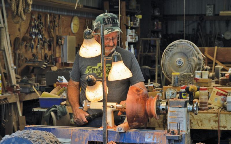 Gene Isenhour looks at a wooden bowl along the lathe he uses to shape his bowls and candle holders. This year alone, Isenhour has made 125 wooden bowls. erick mitchell | dispatch record