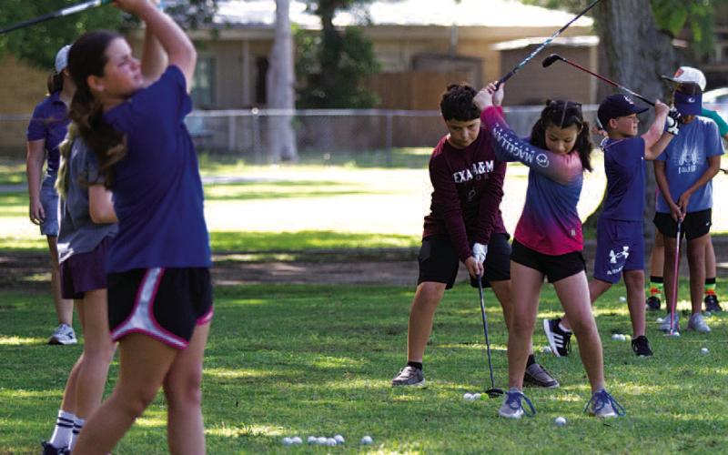 A group of young golfers practice on the driving range at Hancock Park Golf Course on Tuesday at golf camp. HUNTER KING | DISPATCH RECORD