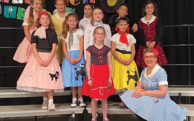 The Jingle Bell Jukebox Drama Club is pictured here: front row, student Madelynn Scott and teacher Linda Lapierre (seated); middle row from left, Madison Orr, Kaylee Berg, Madison Martin and Zoey Rivas; back row, Gabby Schlipp, Hadley Perry, Emma Miller, John Lake and Ava Ramirez. COURTESY PHOTO